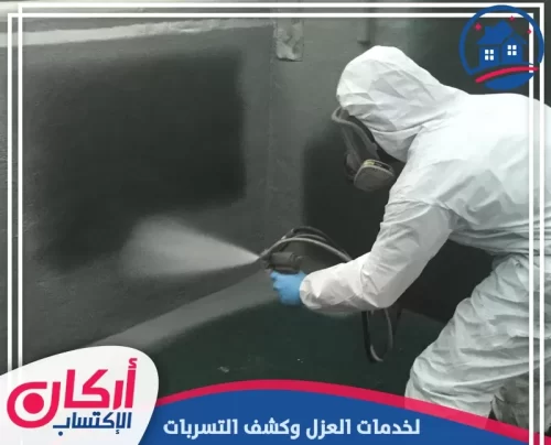 عملية رش مادة عازلة زرقاء اللون فوق طبقة أساس بيضاء لضمان كشف تسربات المياه ومعالجتها نهائياً.